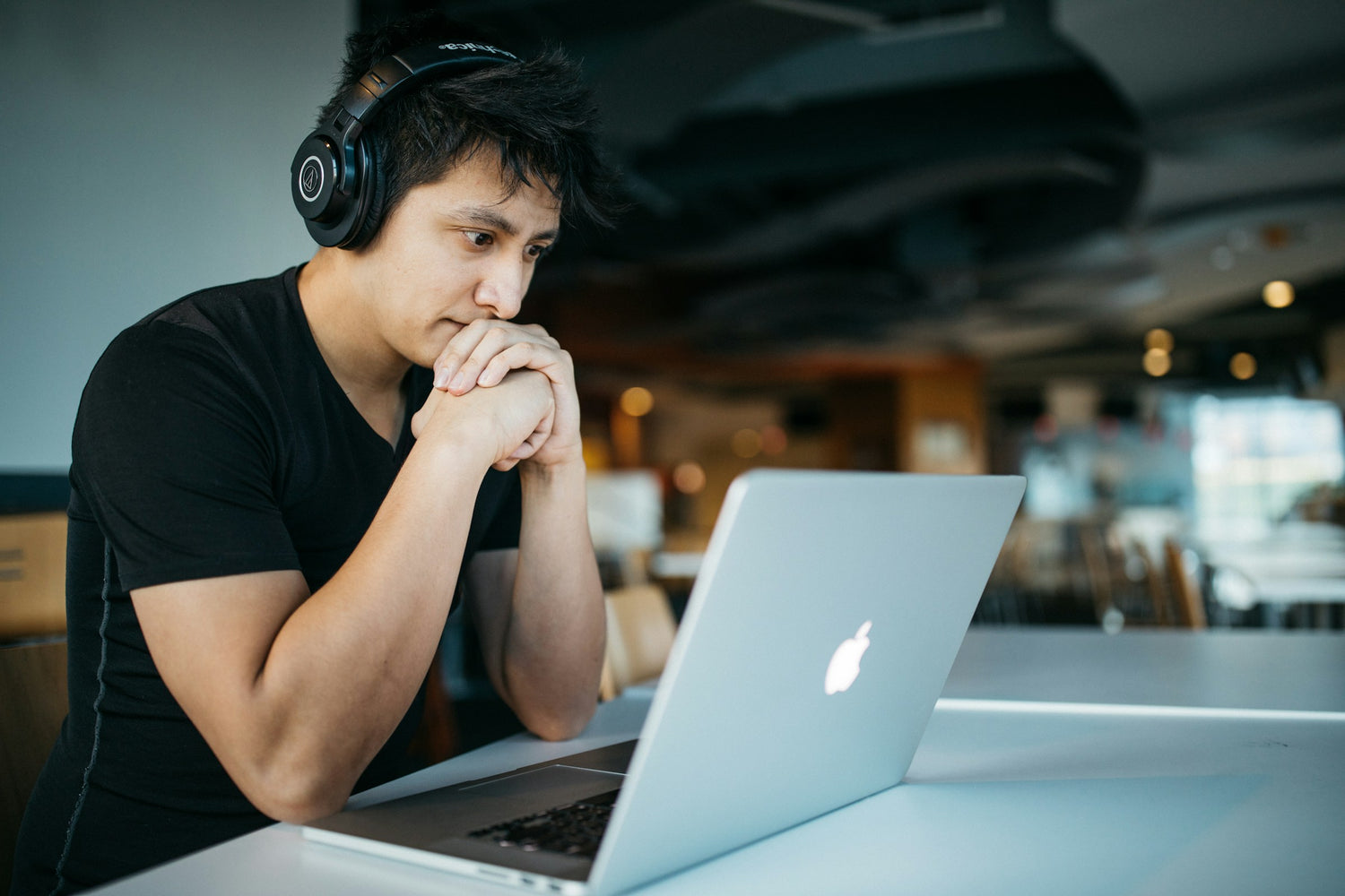 Mann sitzt mit Kopfhörern konzentriert vor dem Laptop