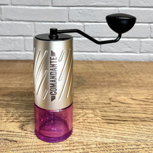 Laden Sie das Bild in den Galerie-Viewer, Comandante C60 Baracuda Handkaffeemühle Velvet Steel mit Bohnenbehälter in Pink auf einer Küchenplatte