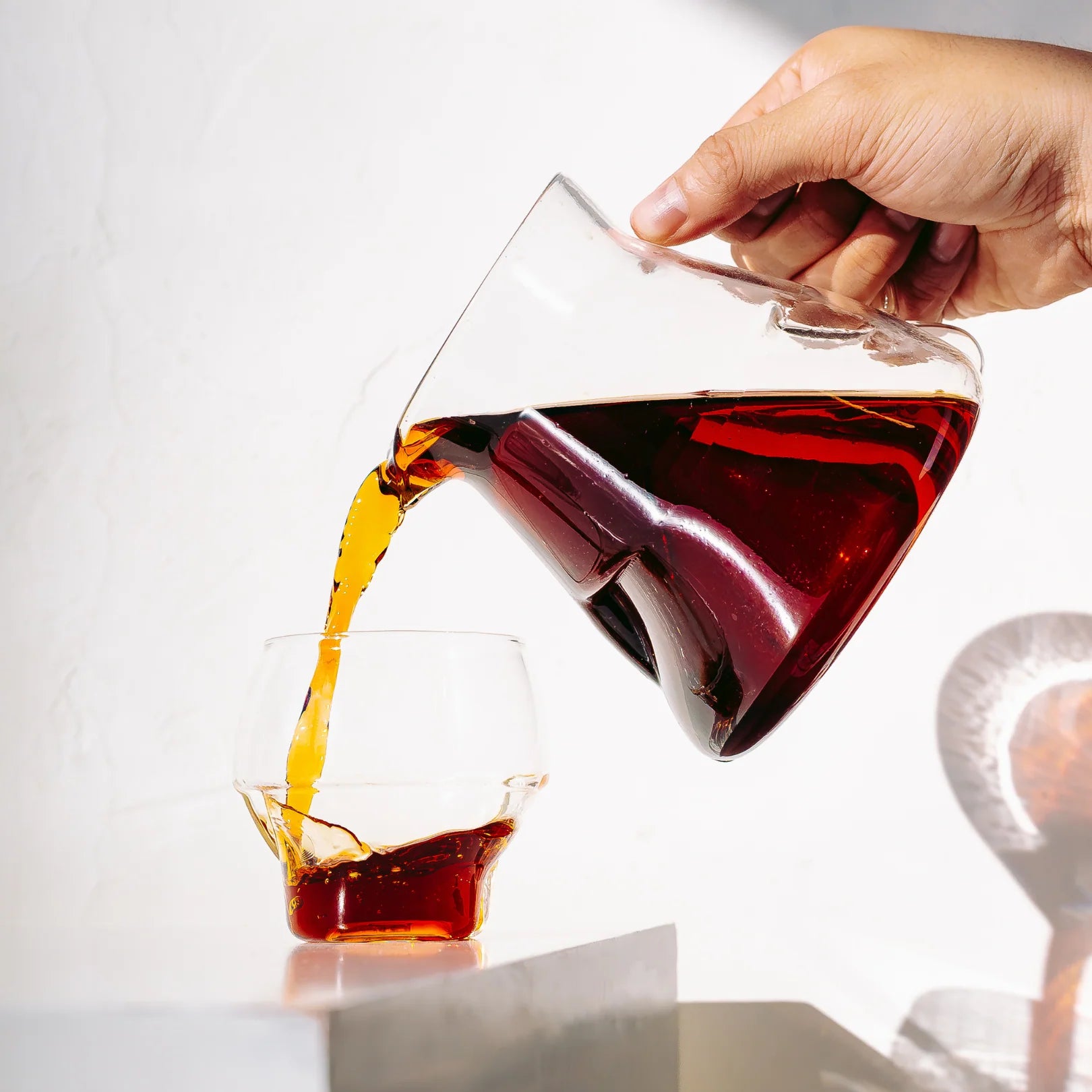 Kaffee wird aus der Icosa Cyclone Carafe in ein Glas eingeschenkt