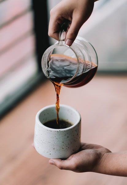Kaffee wird aus einer Kanne in eine Tasse eingeschenkt