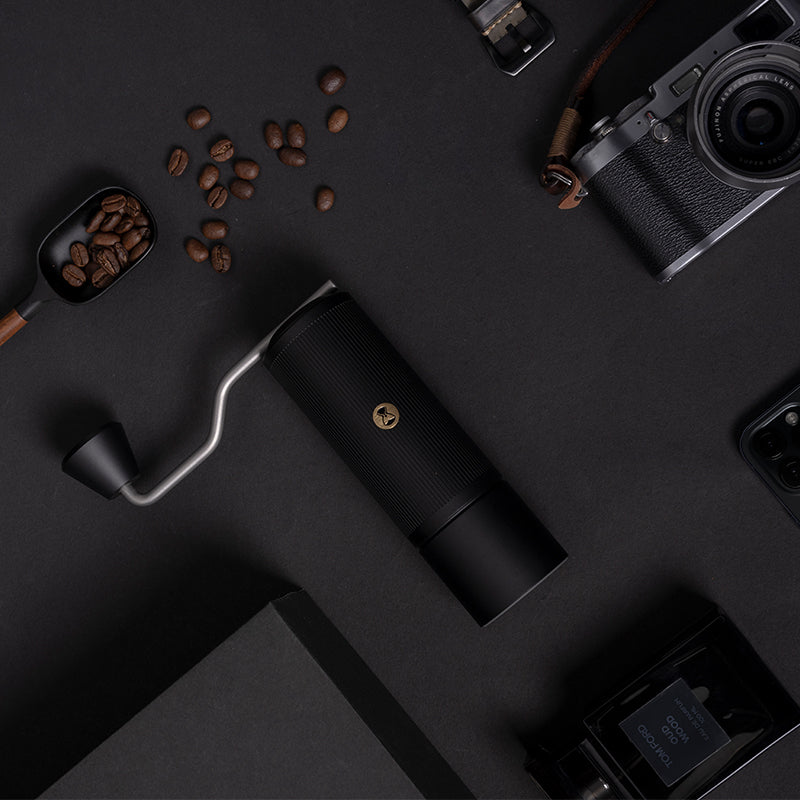 Timemore X-Lite Handmühle schwarz auf schwarzem Hintergrund mit Kaffeebohnen, Kamera, Handy