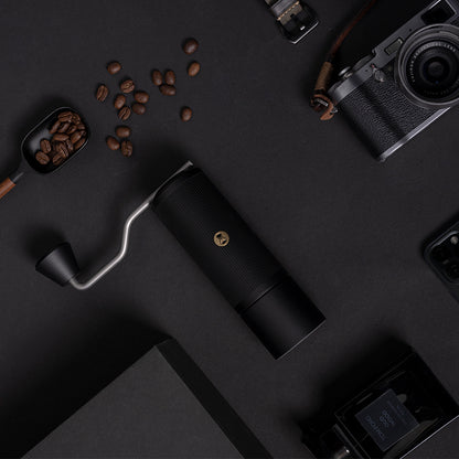 Timemore X-Lite Handmühle schwarz auf schwarzem Hintergrund mit Kaffeebohnen, Kamera, Handy